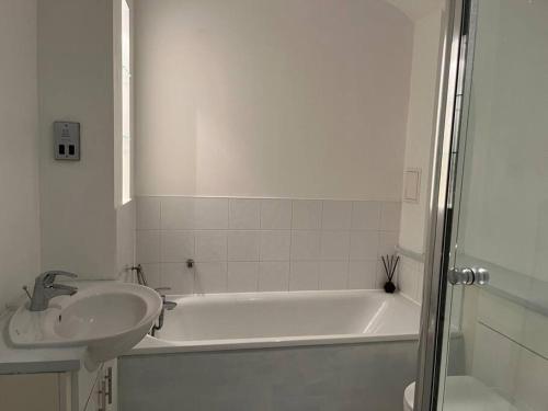 ein Badezimmer mit einem Waschbecken, einer Badewanne und einem Waschbecken in der Unterkunft Bluebell Cottage - private coach house, garage & parking in Greenhithe