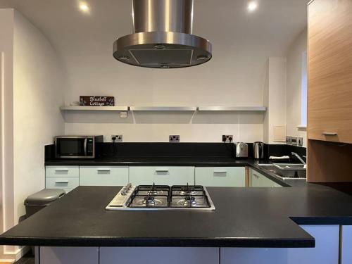 a kitchen with a black counter top with a stove at Bluebell Cottage - private coach house, garage & parking in Greenhithe