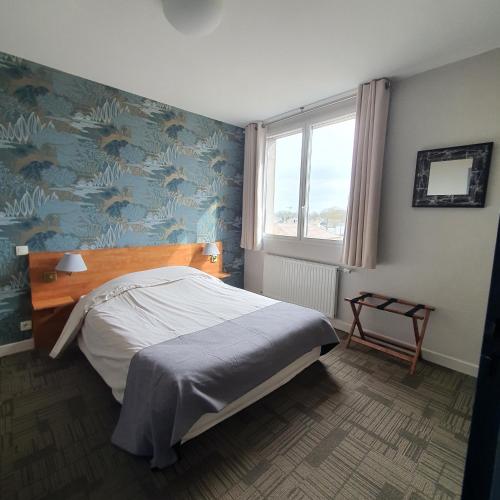 a bedroom with a bed and a blue wall at HOTEL RESTAURANT La CREPERIE Du CHATEAU in Craon