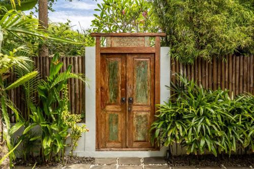 an old wooden door in front of a fence at Rimba Villas Gili Air in Gili Air