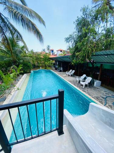 a swimming pool next to a house with a resort at Optimum Residencies in Negombo