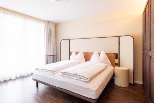 a bedroom with a large bed with white sheets and pillows at EMA House Serviced Apartments Superior Seefeld in Zürich