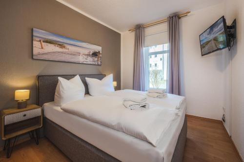 Schlafzimmer mit einem großen weißen Bett und einem Fenster in der Unterkunft Haus Strandoase 27 in Bansin