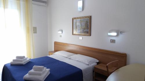 um quarto com uma cama azul com duas toalhas em Hotel Venezia Beach em San Mauro a Mare