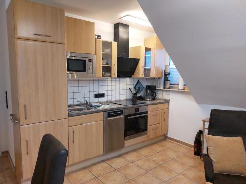 Una cocina con electrodomésticos de acero inoxidable y gabinetes de madera. en Trekvogels Utkiek, en Dornum