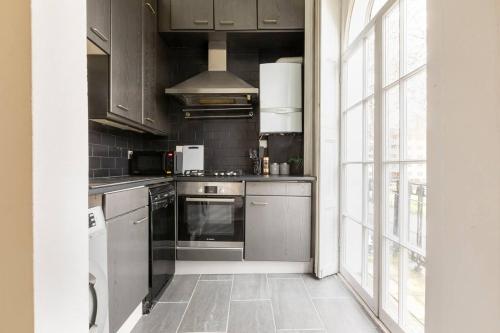 a kitchen with stainless steel appliances and a large window at Cozy Flat in the Heart of London in London