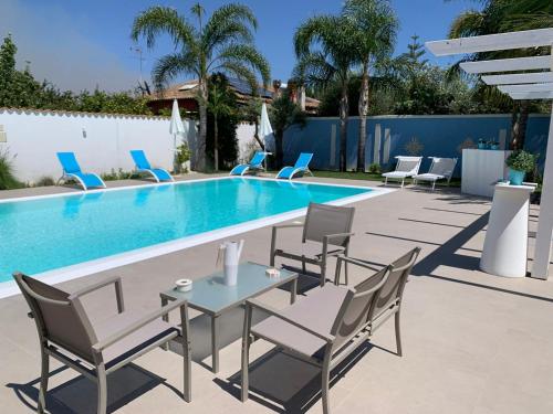 una piscina con sillas y una mesa frente a ella en B&B Villa Eraclea en Villaggio Mosè