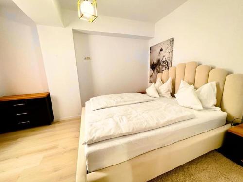 ein Schlafzimmer mit einem großen weißen Bett in einem Zimmer in der Unterkunft City Center Accommodation - 310 in Reşiţa