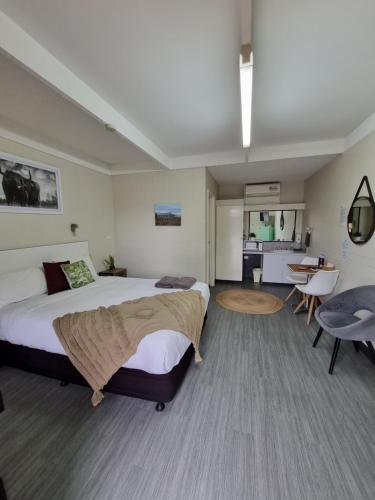 1 dormitorio con 1 cama grande, mesa y sillas en Bidgee Motor Inn, en Hay