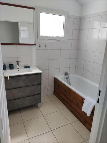 La salle de bains blanche est pourvue d'une baignoire et d'un lavabo. dans l'établissement Maison avec barbecue, à Saint-André
