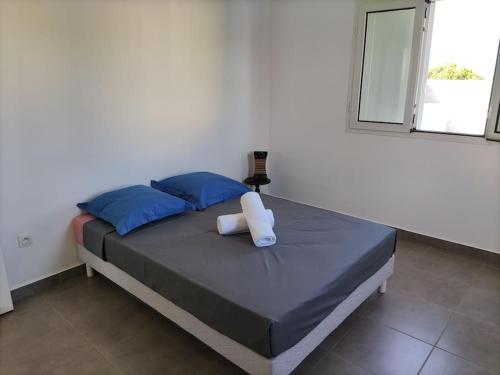 - une chambre avec un lit doté d'oreillers bleus et d'une fenêtre dans l'établissement Maison avec barbecue, à Saint-André