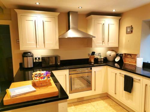 una cocina con armarios blancos y una tabla de cortar de madera en Historic, traditional & Spacious Wiltshire Cottage, en Shrewton