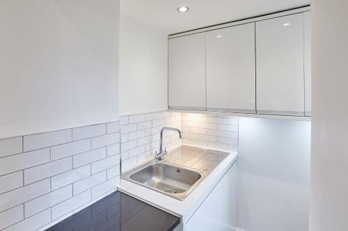 uma cozinha com um lavatório e armários brancos em Apartment 1 - Khyber Lodge Apartments em Whitby