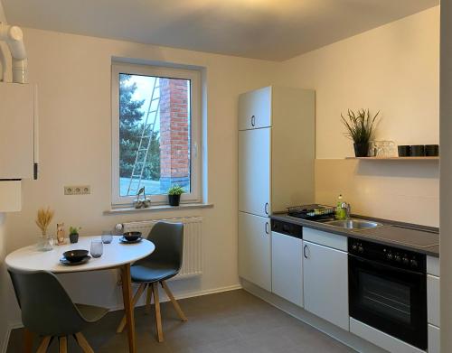 a kitchen with a table and a sink and a refrigerator at Elbnahe Ferienwohnung mit 2 Schlafzimmern in Coswig