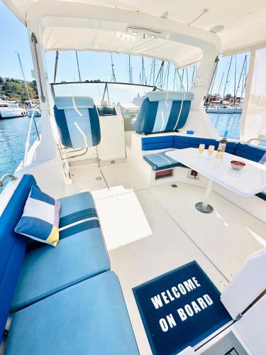 un bateau avec des sièges bleus et un panneau de bienvenue à bord dans l'établissement HEBERGEMENTS BATEAUX A QUAI, à Porquerolles