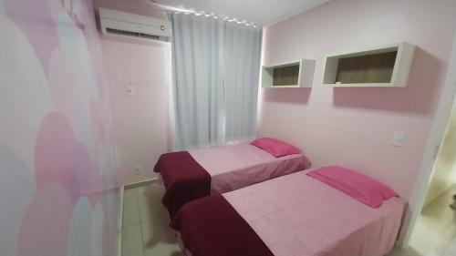 duas camas num quarto com lençóis rosa e roxo em APTO ACONCHEGANTE 1KM DA Praia do aracagy e 4KM DA Litorânea em São Luís