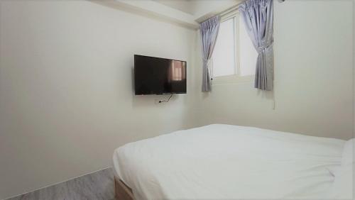 a bedroom with a bed and a flat screen tv on the wall at Fengchia Bichon B&B in Taichung