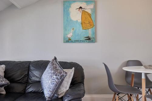 ein schwarzes Ledersofa in einem Wohnzimmer mit einem Bild an der Wand in der Unterkunft Apartment 4, Khyber Lodge Apartment Whitby in Whitby