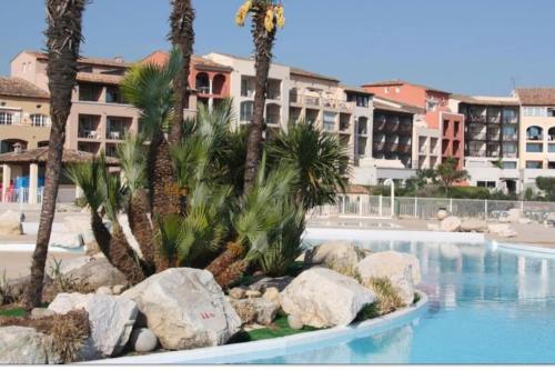 una piscina con palmeras y un edificio en Appartement climatisé bord de plage et piscine, en Cogolin