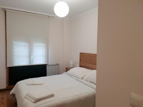 een slaapkamer met een wit bed en een raam bij PIEDAD FERNANDEZ FERNANDEZ GESTION DE INMUEBLES - III in O Barqueiro