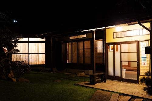 伊豆の宿　静海 في إيتو: منزل في الليل مع مقعد أمامه