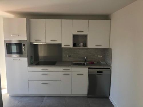 a kitchen with white cabinets and a sink at Vakantiewoning De Kassei Geraardsbergen max 12personen in Geraardsbergen