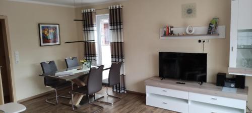 a dining room with a table with chairs and a television at Ferienwohnung Reddemann in Westerstede