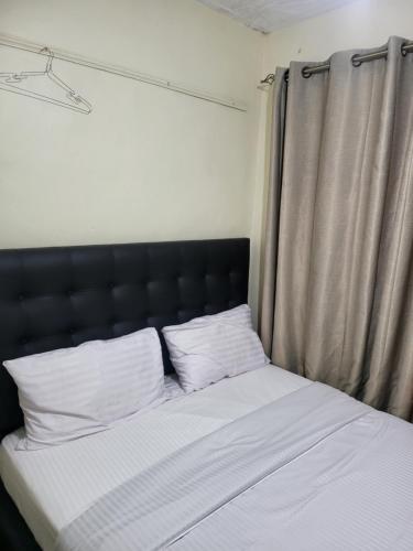 a bed with a black headboard and white pillows at G&G Homes Ngala Nakuru in Nakuru