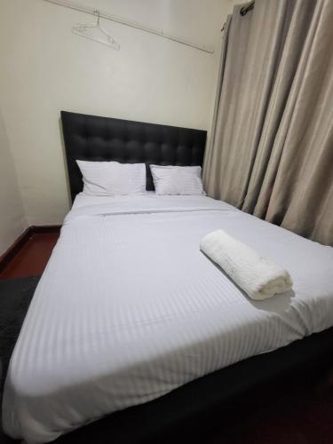 a bed with a black headboard and a white blanket at G&G Homes Ngala Nakuru in Nakuru