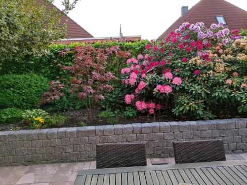 a garden with pink flowers on a retaining wall at Ferienwohnung Reddemann in Westerstede