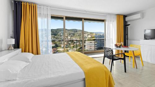 a bedroom with a bed and a table with a view at Cannes Marina Appart Hotel Mandelieu in Mandelieu-la-Napoule