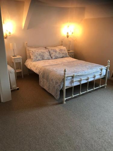 a bed in a bedroom with two lights on the wall at The Malt Scoop Inn in Merton