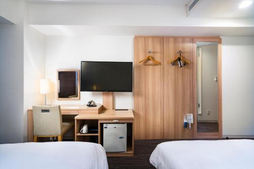 een hotelkamer met 2 bedden en een bureau bij KOKO HOTEL Sapporo Ekimae in Sapporo
