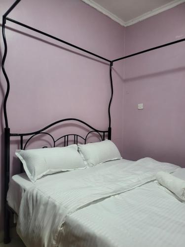 a bed with a black frame and white sheets and pillows at G&G Homes Naka Nakuru in Nakuru