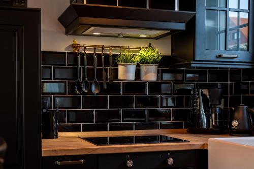 a kitchen with black tiled wall with potted plants at Blablu - Ferienhaus Bäckerei Koch in Blankenburg