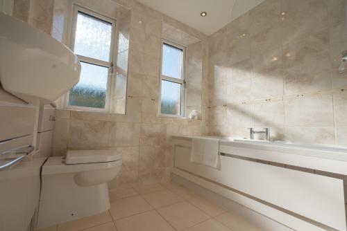 a bathroom with a tub and a toilet and a sink at Ledgowan Lodge Hotel in Achnasheen