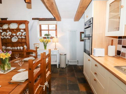 uma cozinha com armários brancos e uma mesa de madeira em Two Shoes Cottage em Okehampton
