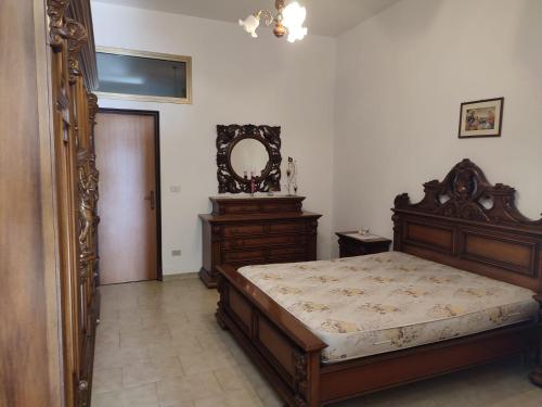 a bedroom with a wooden bed and a mirror at Campolo Apartment in Reggio Calabria