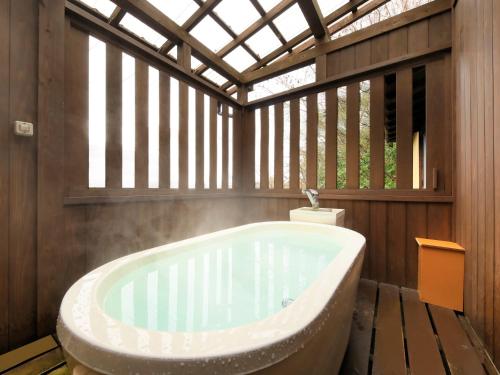 a bath tub in a bathroom with a window at Saikatei Jidaiya in Kaminoyama