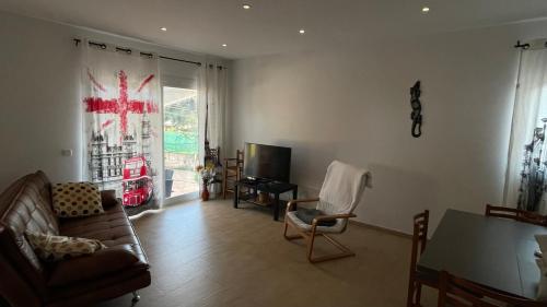 a living room with a couch and chairs and a television at Aina in Cala Pi