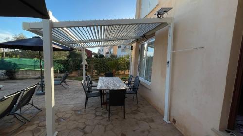a patio with a table and chairs and an umbrella at Aina in Cala Pi