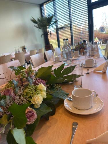 a long wooden table with flowers and a cup of coffee at Nordic Avantage Hotel in Kiel