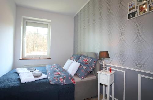 Un dormitorio con una cama con sábanas azules y una ventana. en Apartament Winston, en Szczawno-Zdrój