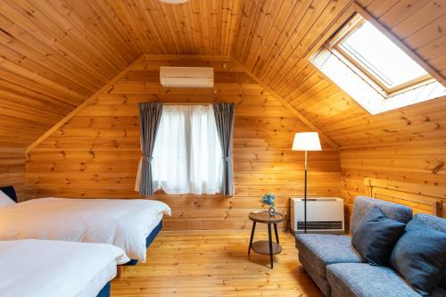 - une chambre dans une cabane en rondins avec un lit et un canapé dans l'établissement スイートヴィラ那須高原ログMoiMoi, à Nasu