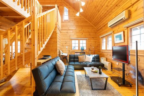 a living room with a couch and a tv at Suite Villa Nasukogen Log MoiMoi in Nasu