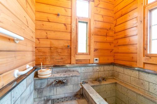 La salle de bains est pourvue de murs en bois et d'une baignoire. dans l'établissement スイートヴィラ那須高原ログMoiMoi, à Nasu