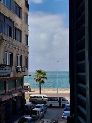 vistas a la playa desde un edificio con coches aparcados en اللوكاندة الجديدة New Hotel en Alexandría