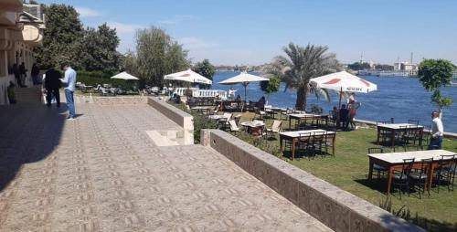 a walkway with tables and tables and chairs next to the water at الميناء السياحي جزيرة القرنة in Luxor