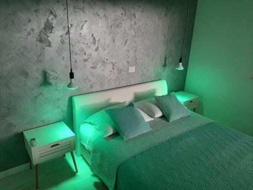ein grünes Schlafzimmer mit einem Bett und zwei Nachttischen in der Unterkunft Apartments Delfin - sea view in Prvić Šepurine