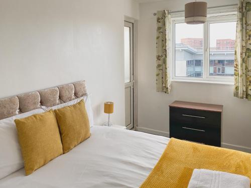 een slaapkamer met een bed met gele kussens en een raam bij 3 Bedroom flat in Hockley Birmingham near city centre, comfy and convenient in Birmingham